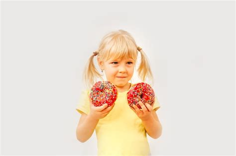 Ni A Linda Comiendo Donas Dulces Sobre Un Fondo Claro Foto Premium