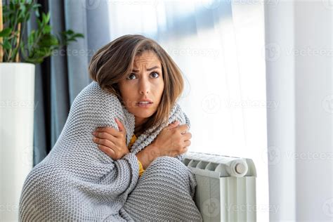 Unwell woman renter in blanket sit in cold living room hand on old