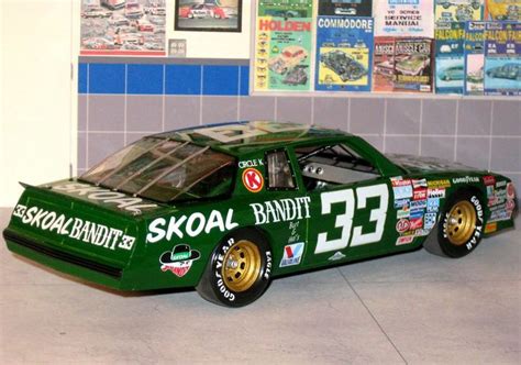 a green race car with gold rims parked in front of posters on the wall