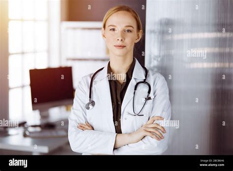 Cheerful Smiling Female Doctor Standing With Arms Crossed In Clinic