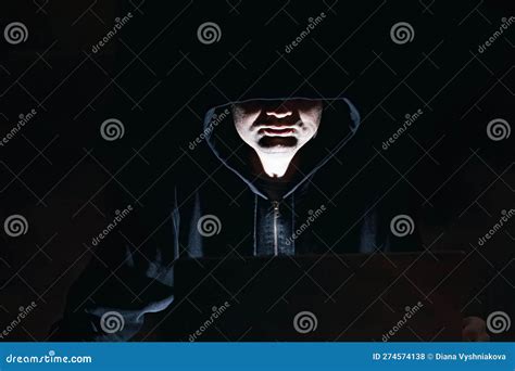 Man In The Hoodie Sitting In Front Of The Laptop At Night Hacker