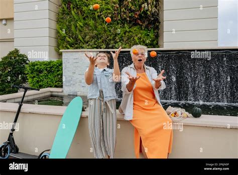 Happy Grandmother And Granddaughter Playing With Mandarins Stock Photo