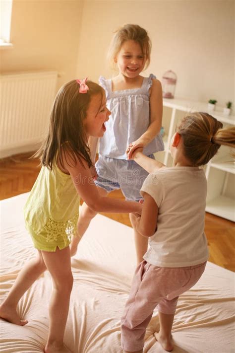 Trois Petites Filles S Asseyant Sur Le Lit Et Regardant L Appareil