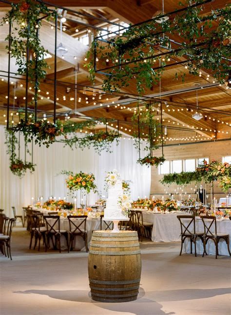 An Indoor Venue With Tables And Chairs Covered In Greenery