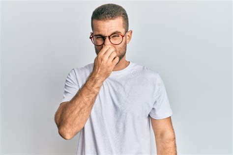 Young Caucasian Man Wearing Casual Clothes And Glasses Smelling