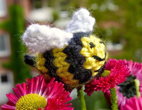 A Close Up Of A Stuffed Bee On Some Flowers With Buildings In The Back