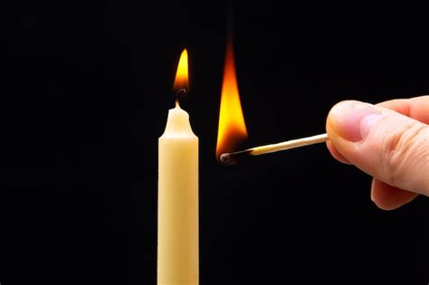 Premium Photo Lighting A Candle With A Wooden Match On A Dark