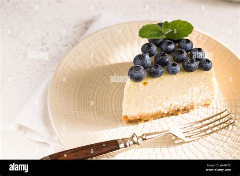 Slice Of Classical New York Cheesecake With Blueberries On White Plate