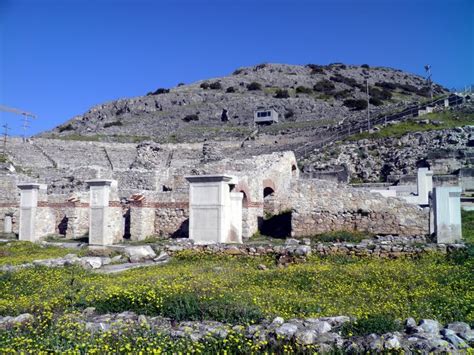 An Old Building In The Middle Of A Field With Yellow Flowers Growing On