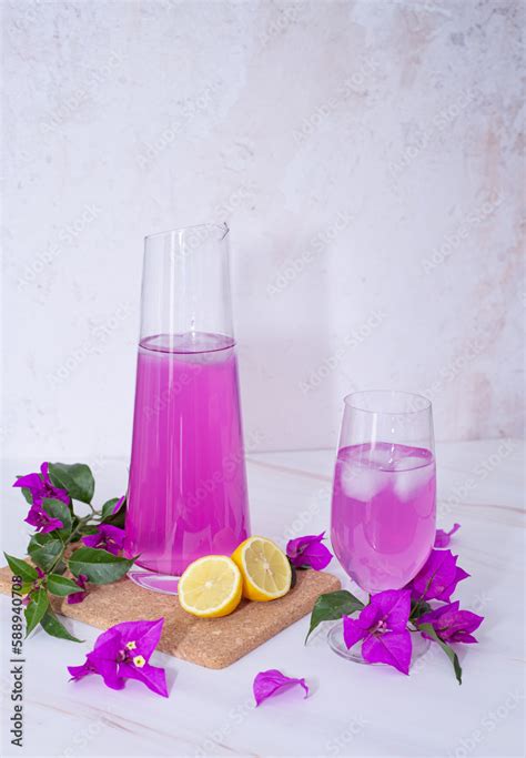 Garrafa con limonada rosa y copa con bebida de limonada rosa con limón