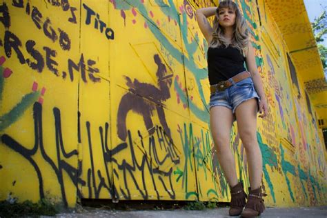 A Woman Standing Next To A Yellow Wall With Graffiti On It S Sides And