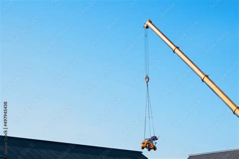 Mobile crane lifting telehandler above the building to place it in the ...