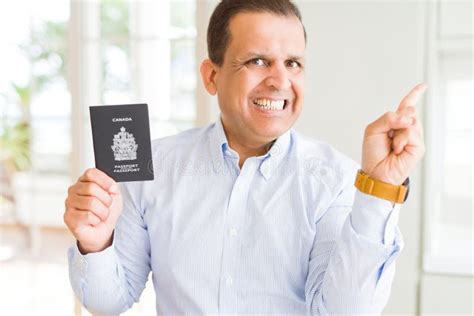 Middle Age Man Holding Holding Canadian Passport Very Happy Pointing With Hand And Finger To The