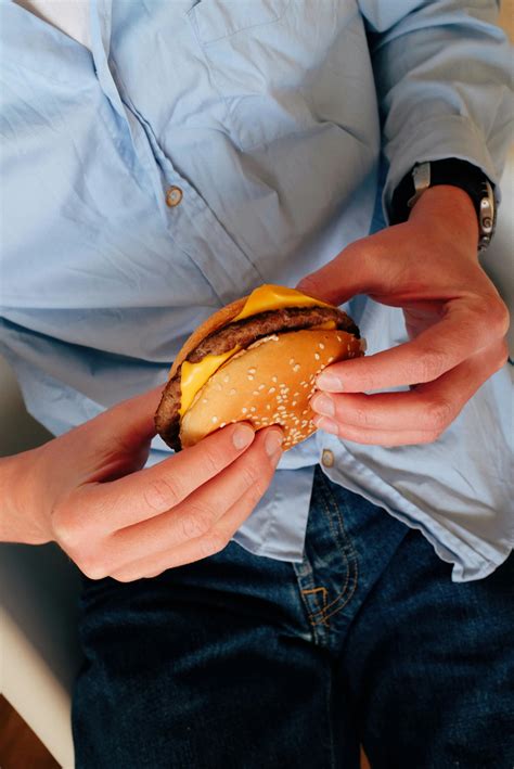 Anonymous man eating burger on chair · Free Stock Photo