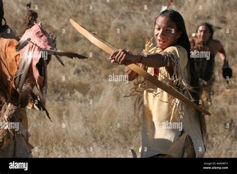 Three Native American Indian men hunting with a bow and arrow in pursuit of game in the dry ...