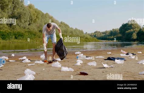 Man Collects Plastic Trash On The Banks Of Polluted River And Shows