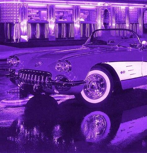 an old car parked in front of a building with purple lights on it's side