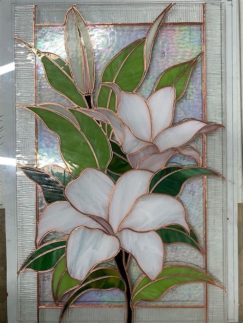 A Stained Glass Window With White Flowers And Green Leaves