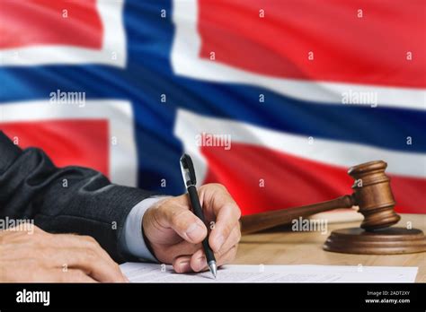 Judge Writing On Paper In Courtroom With Norway Flag Background Wooden