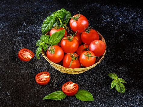 Colheita De Tomates Vermelhos Maduros Em Cesta De Palha E Folhas Verdes