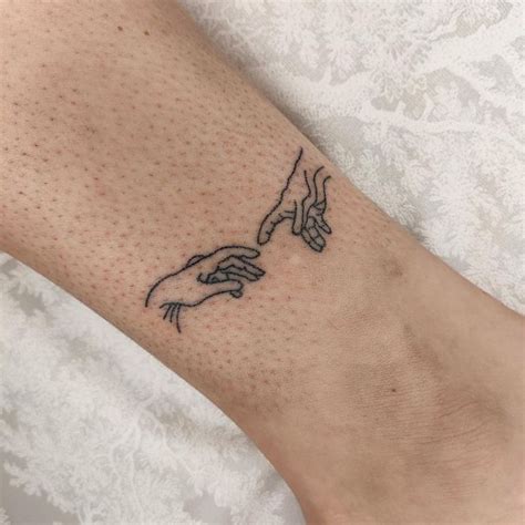 A Woman S Foot With A Tattoo On It That Has Two Hands Touching Each Other