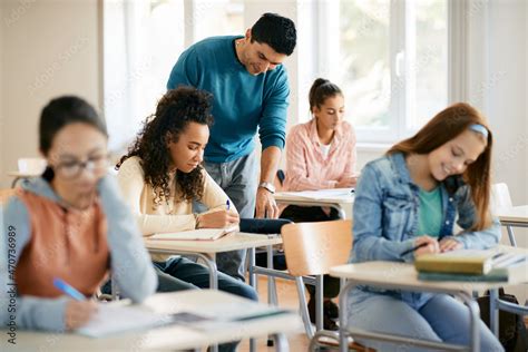 Happy teacher assisting high school student with a lecture in the classroom. Stock Photo | Adobe ...