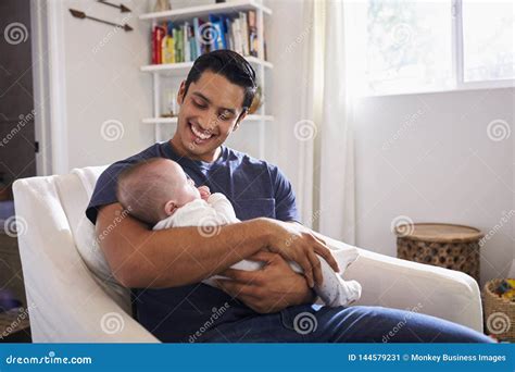 Proud Hispanic Father Sits Holding His Four Month Old Son In His Arms