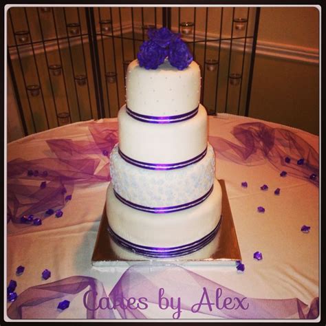 A Three Tiered Wedding Cake With Purple Flowers On The Top And Bottom