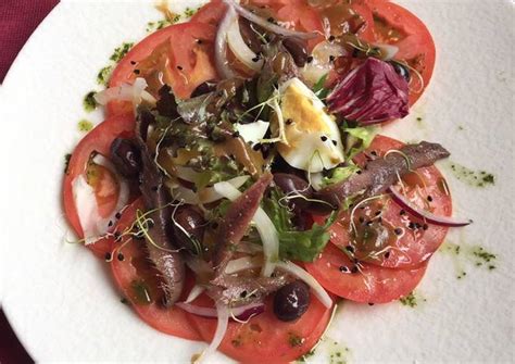 Ensalada de tomate con anchoas en salazón huevo cebolla y brotes con