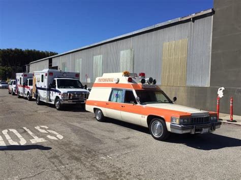 Several Ambulances Parked In Front Of A Building With An Orange And