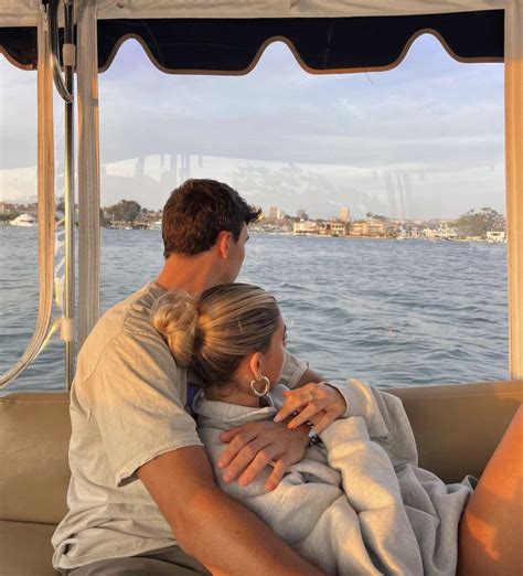 A Man And Woman Sitting On The Back Of A Boat With Their Arms Around