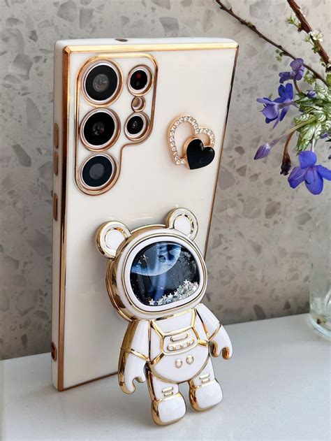 A White And Gold Cell Phone Case With An Astronaut Teddy Bear In The