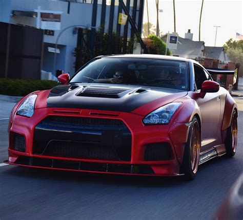 A Red And Black Sports Car Driving Down The Street