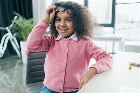 Smiling African American Girl With Eyeglasses Sitting In Office Stock