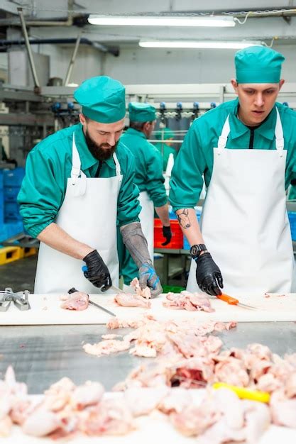 Dos hombres con batas verdes cortan carne en una fábrica Foto Premium