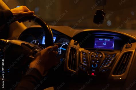 A late night ride, dark moody car interior with lonely driver hands on ...