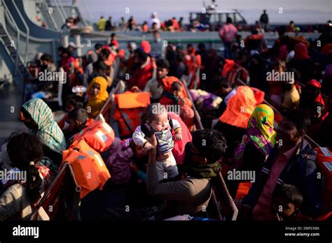 A Rohingya Refugee Lifts An Infant As They Wait In A Naval Ship To Be Transported To An Isolated