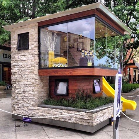 A Small House Made Out Of Bricks And Glass With A Slide In The Front Yard