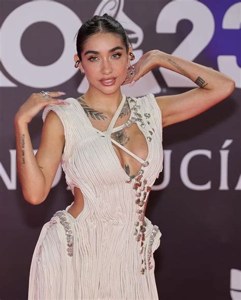 A Woman In A White Dress Posing For The Camera With Her Hands Behind