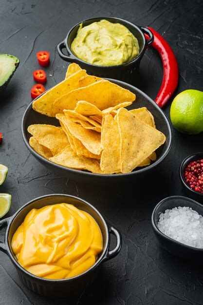 Premium Photo | Nachos and guacamole and cheese sauces, on black table