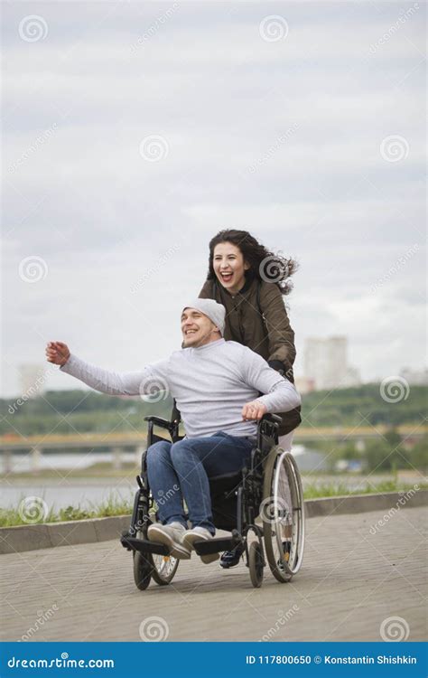 Cheerful Woman With Young Disabled Man In Wheelchair Running On The