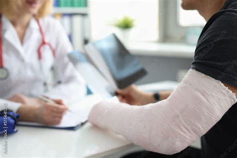 Doctor conducts medical consultation with patient with cast on arm Stock Photo | Adobe Stock