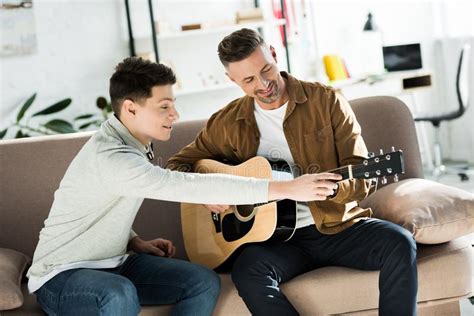 Hijo Adolescente Enseñando a Su Padre Tocar Guitarra Acústica Foto de