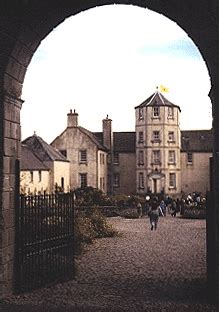 An Archway Leading To A Building With People Walking Around It