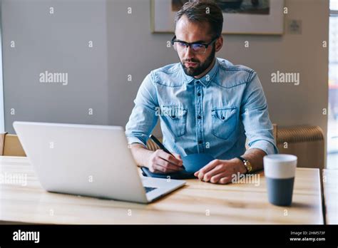 Focused Man Looking At Laptop Taking Notes Stock Photo Alamy