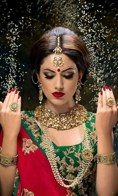 A Woman In A Red And Green Sari With Her Hands On Her Chest Surrounded