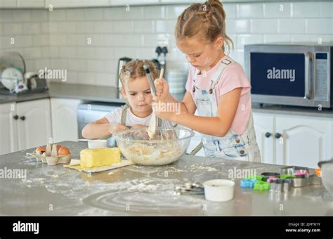 Two Messy Little Girls Baking In The Kitchen At Home Caucasian Focused