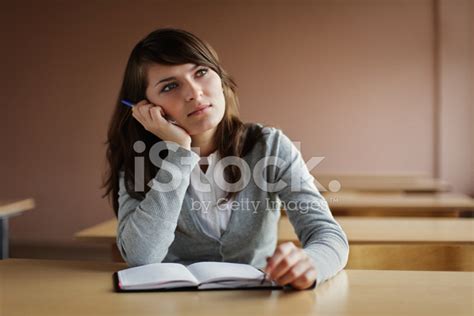 Distracted Female Student Sitting With Pen And Notebook In Class Stock