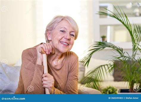 Elder Lady Sitting On The Couch With Wooden Walking Stick And Smiling