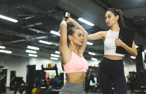 Workout With Personal Trainer Instructor Helping Girl In Gym Stock